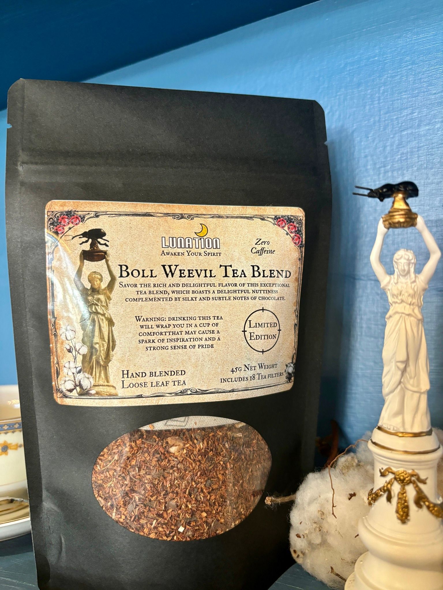 A bag of rice is sitting on a table next to a statue.