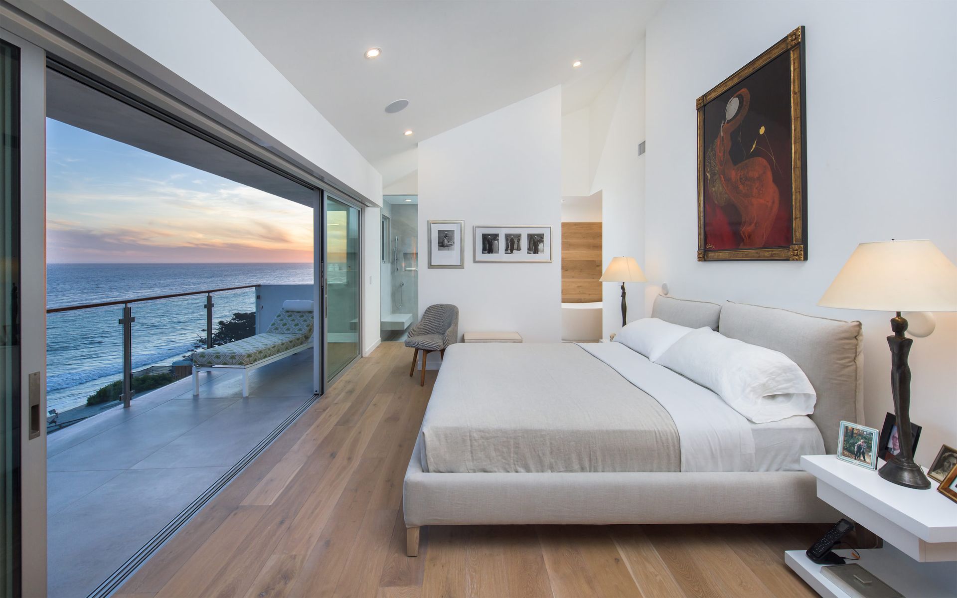 The bedroom of the Broad Beach Modern remodel in Malibu, CA, with a large bed and a balcony overlooking the ocean.