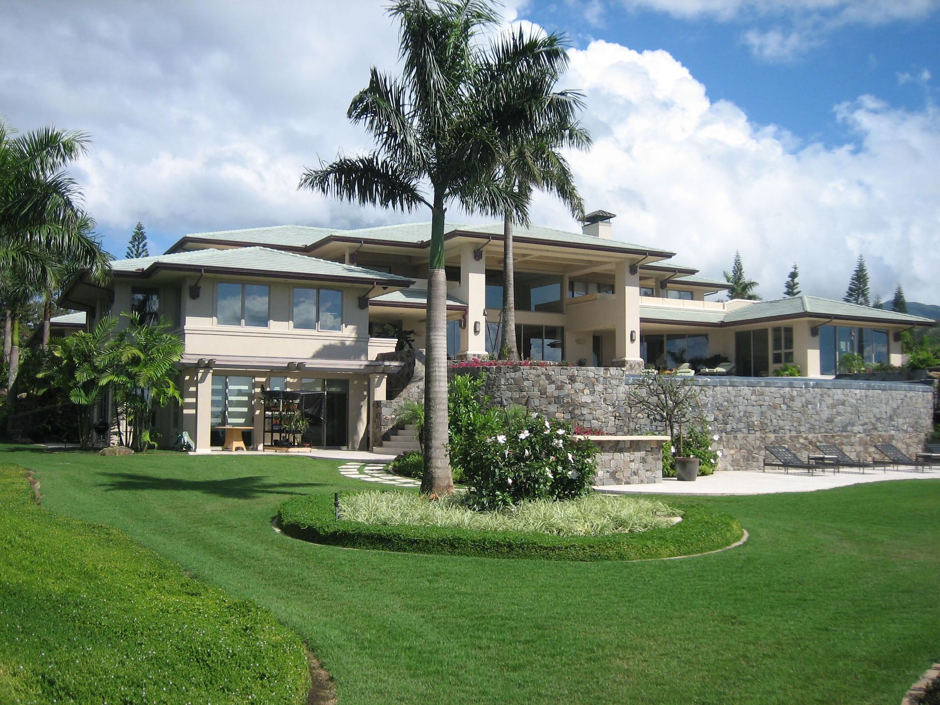 The Kapalua estate home is viewed from the rear with palm trees in the foreground