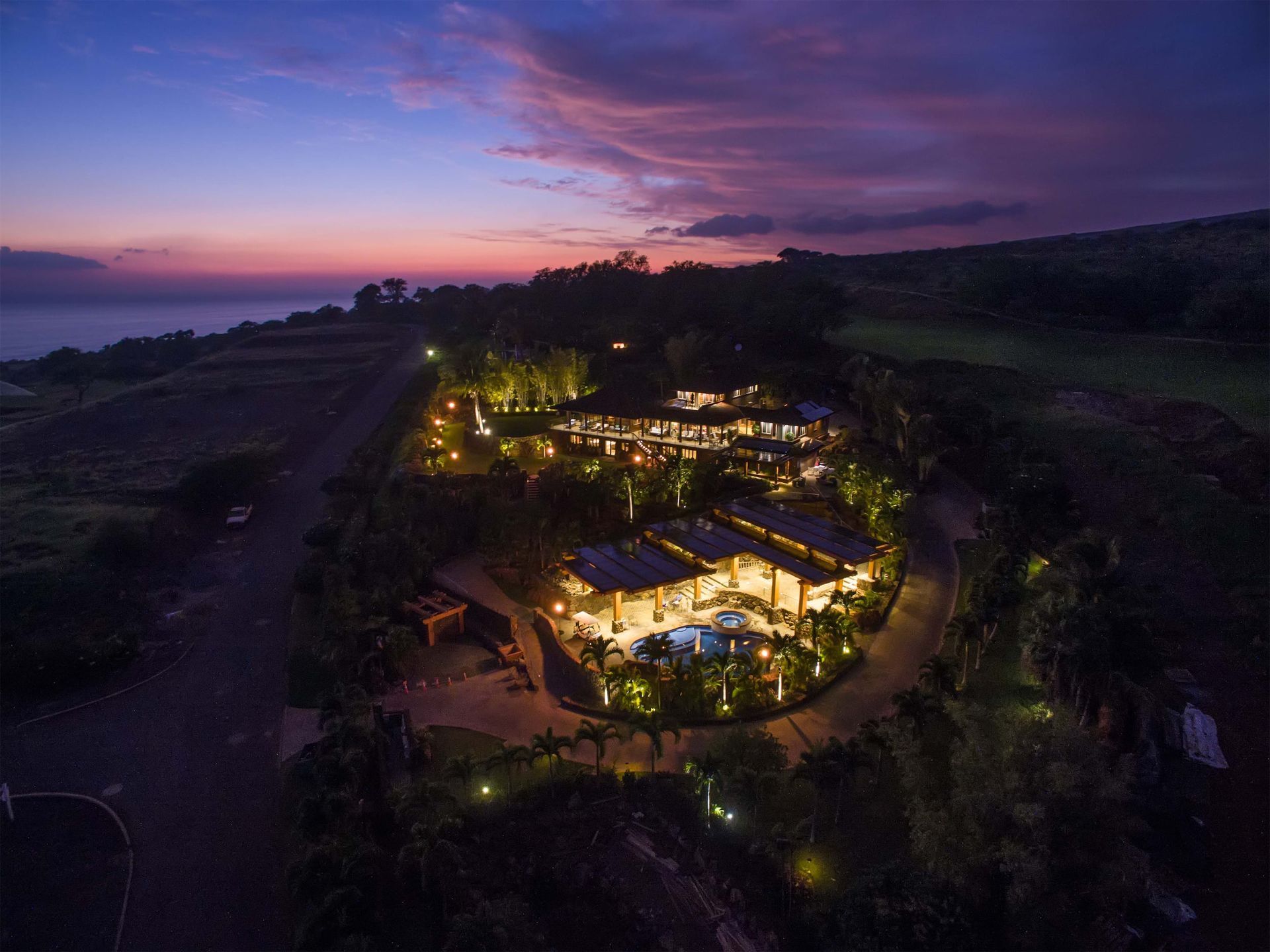 An aerial view of the Lanai Estate in Maui, HI, at night with a sunset in the background.