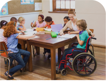 A girl in a wheelchair is sitting at a table with other children.