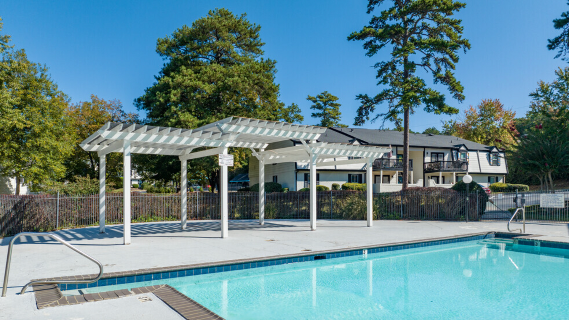 A large swimming pool with a pergola and a house in the background at Dwell @ 750