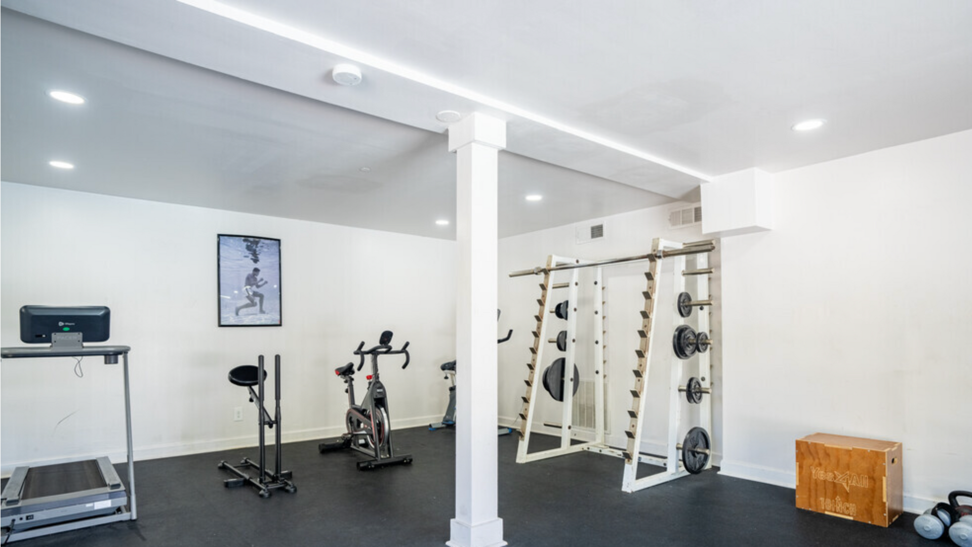 A gym with a treadmill , exercise bikes , and weights at Dwell @ 750