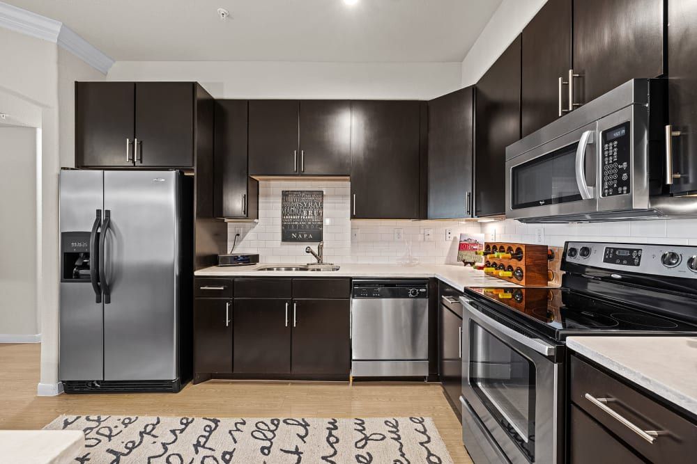 A kitchen with stainless steel appliances and brown cabinets at Marquis at the Reserve in Katy, TX.