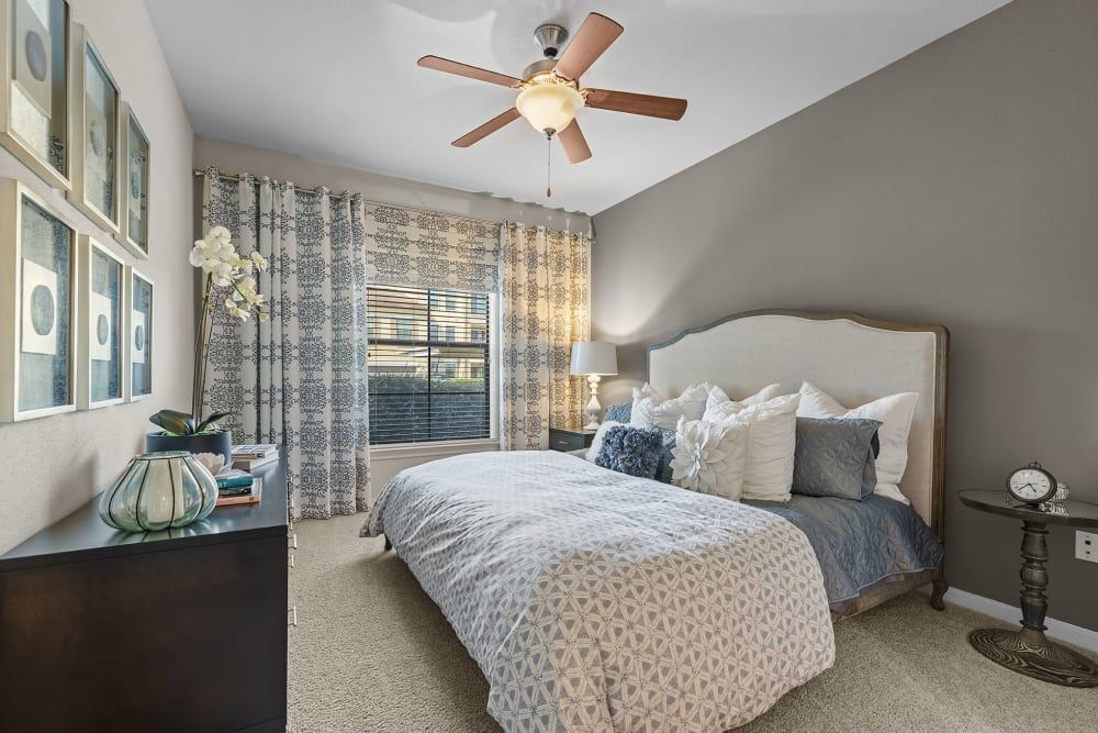 Modern bedroom with a large bed and a ceiling fan at Marquis at the Reserve in Katy, TX.