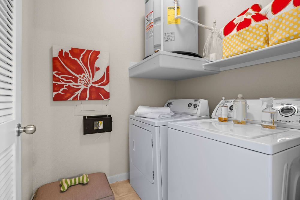 A laundry room with a washer and dryer and a picture on the wall at Marquis at the Reserve in Katy, TX.