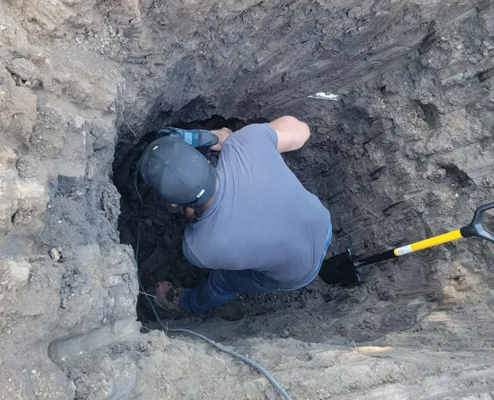 A man is digging in the dirt with a shovel