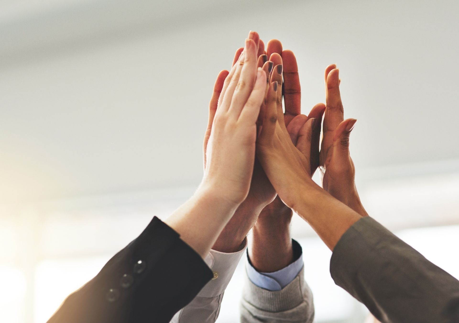 Hands raised in a high five, emphasizing teamwork and achievement in an office setting.