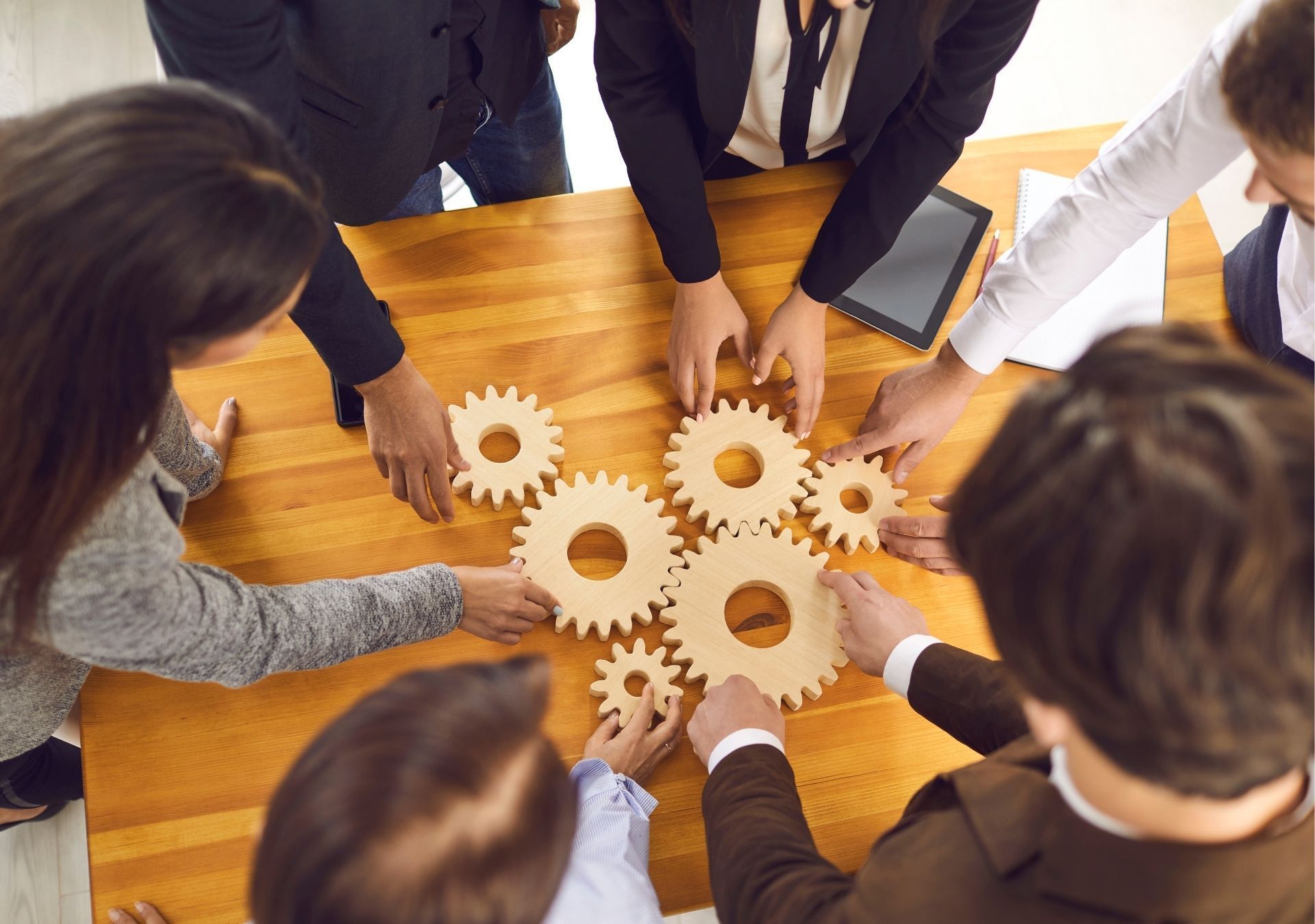 People around a table fitting wooden gears together.