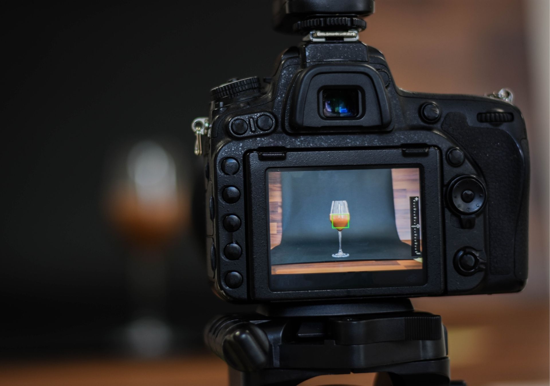 DSLR camera on tripod, photographing a cocktail. The drink is centered on a black backdrop.
