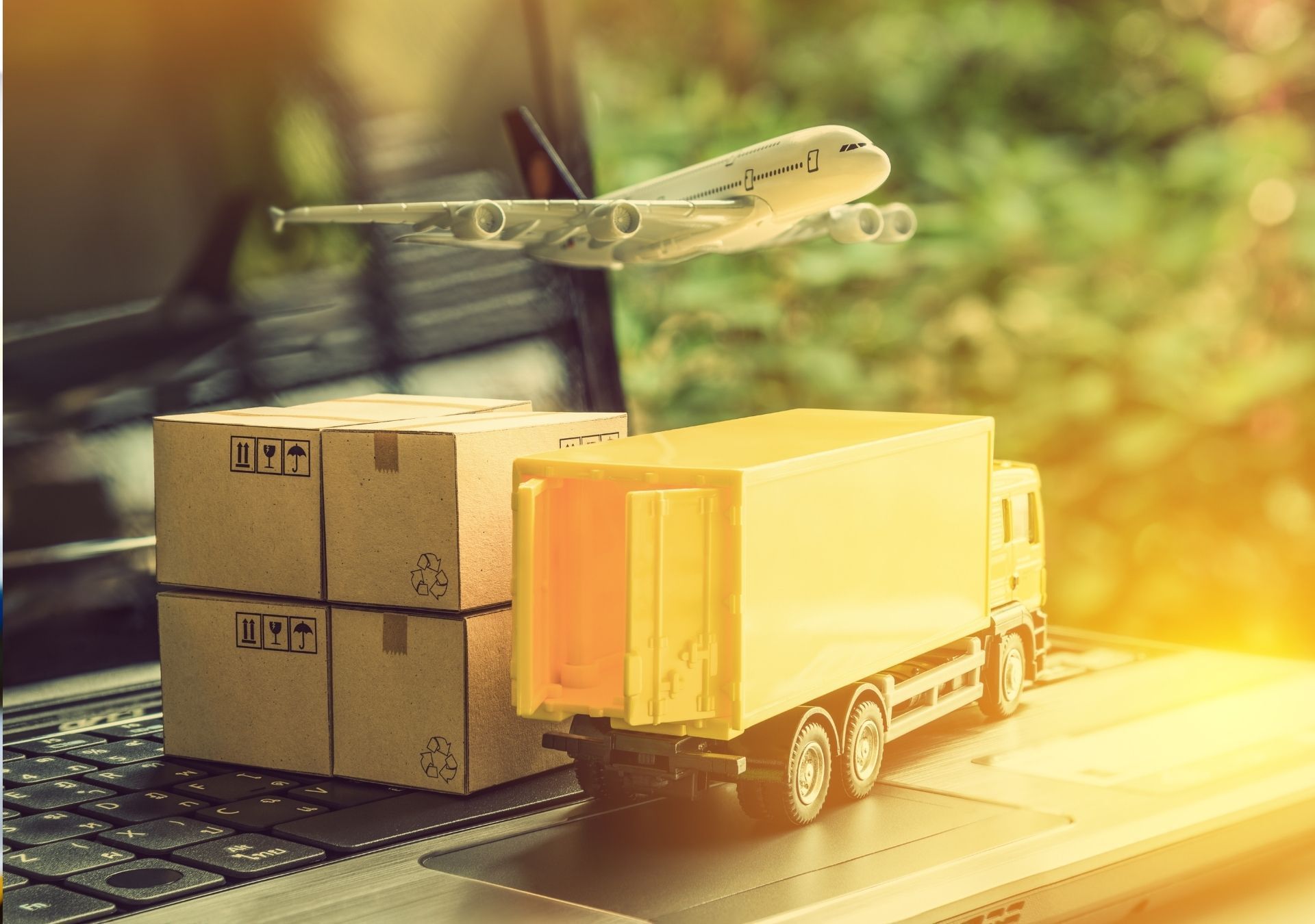 Toy airplane, truck, and packages on a laptop, representing global shipping and logistics.
