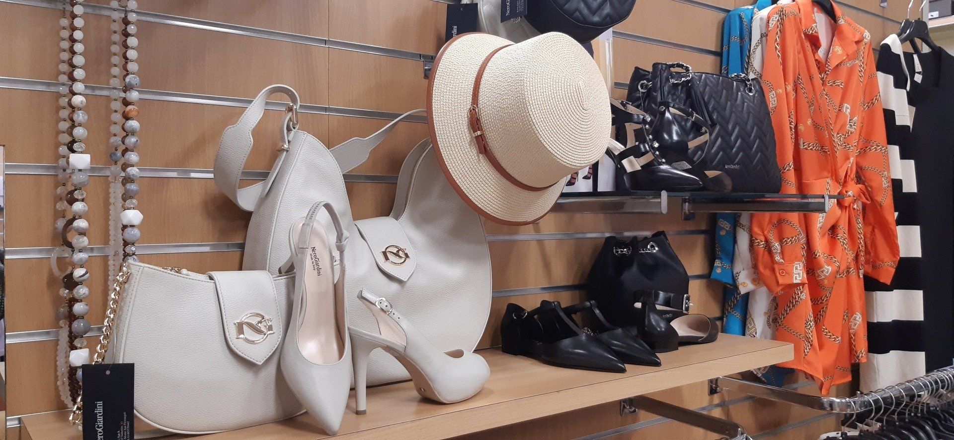 Un'esposizione di cappelli, scarpe, borse e vestiti in un negozio.