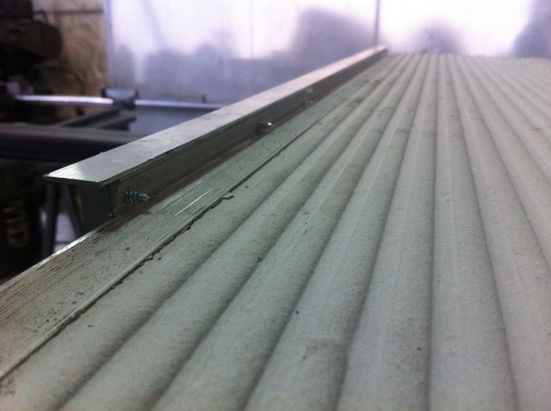 Un elemento di finitura metallico installato sul bordo di una superficie scanalata di colore chiaro.