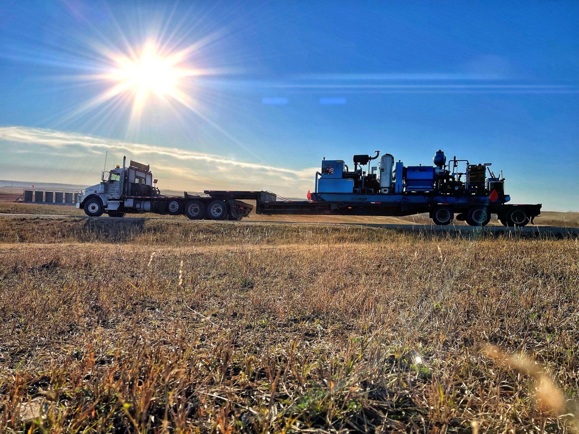semi in a field carrying oil drilling equipment