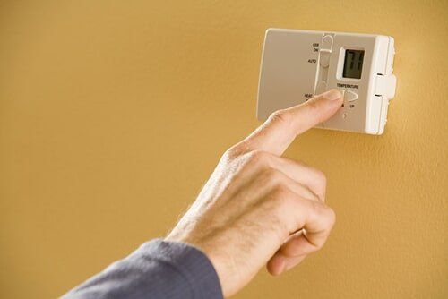 Person adjusting thermostat, Air Conditioning and Heating Systems in Ocean, NJ