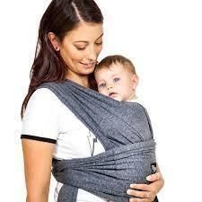 Una donna tiene in braccio un bambino in una fascia.