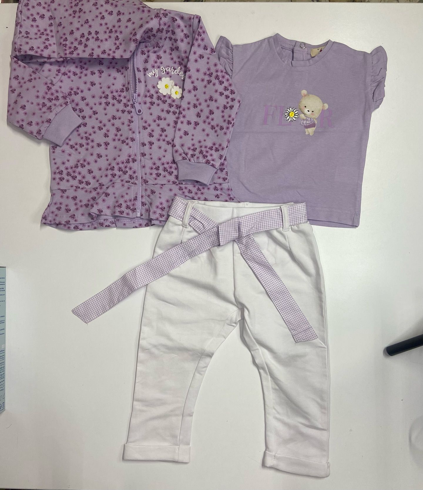 Una camicia viola e pantaloni bianchi sono su un tavolo bianco.