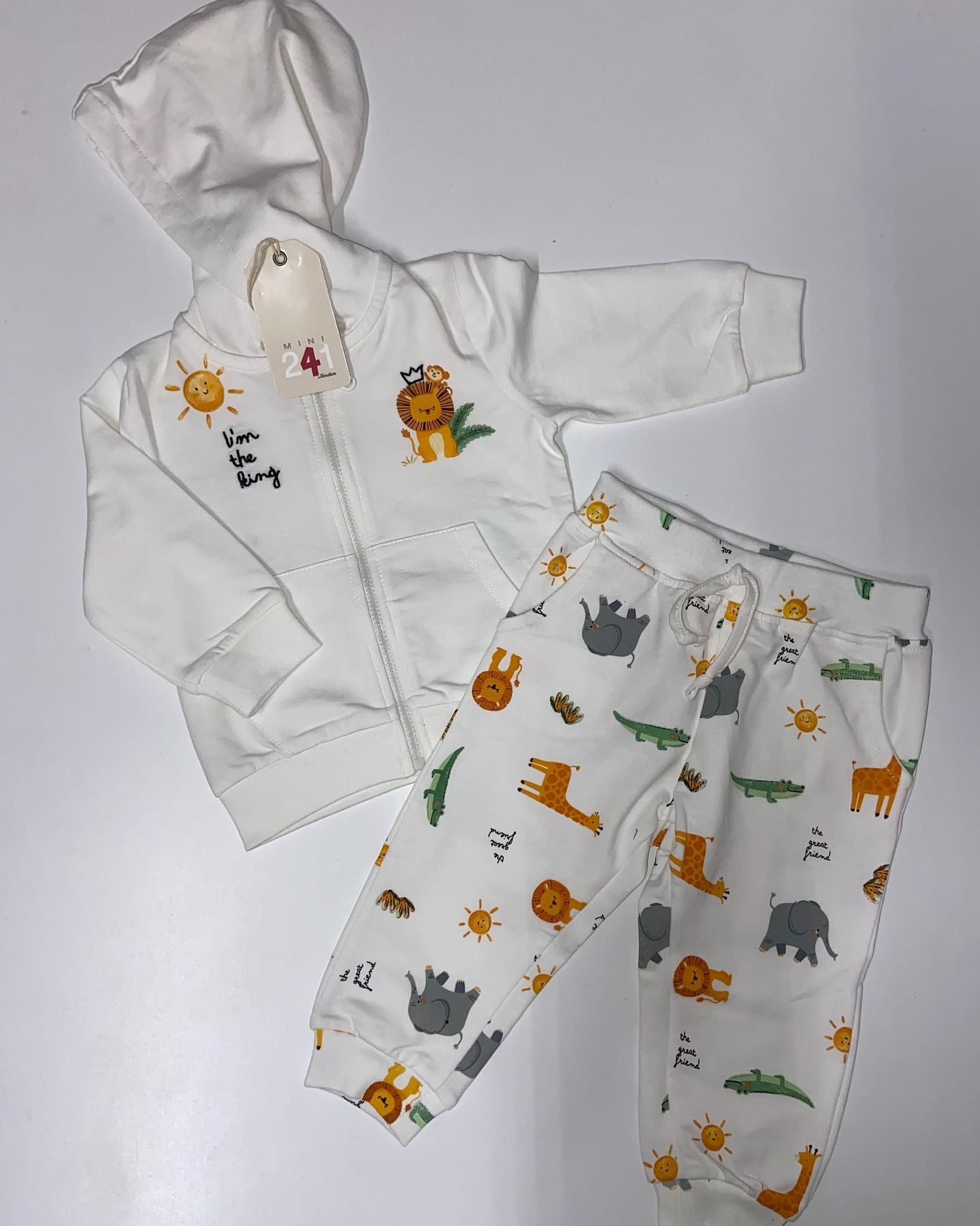 Un bambino indossa una felpa bianca con cappuccio e pantaloni con degli animali stampati.