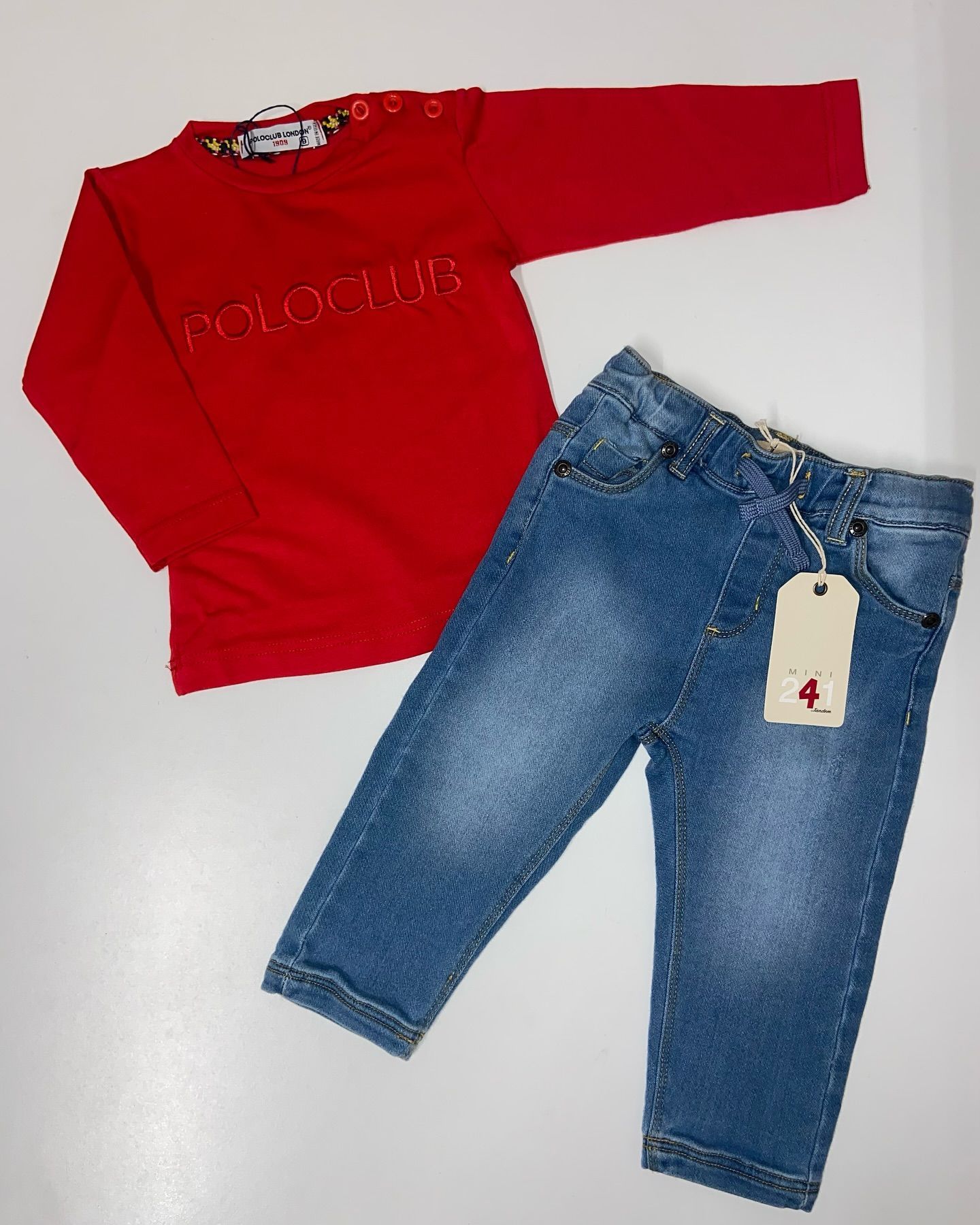 Una maglietta rossa e dei jeans blu sono su una superficie bianca