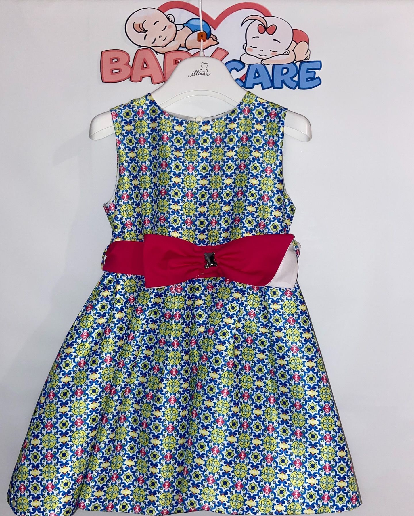 Un vestito blu e verde con un fiocco rosso è appeso a una gruccia