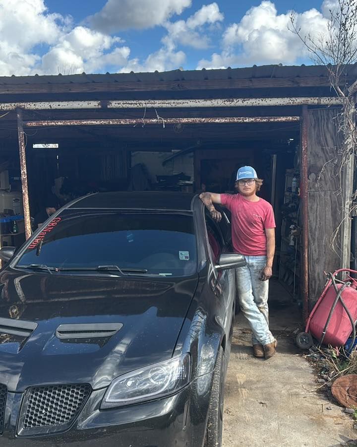 Woman in straw hat smiles, holding wine glass near a lake.