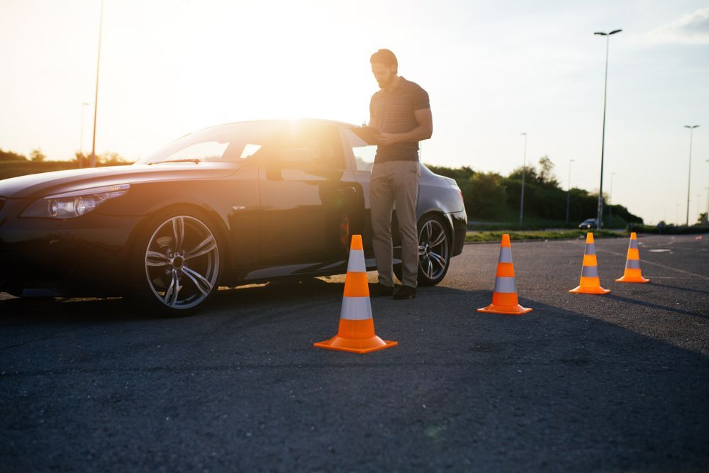 A Man Is Standing Next to A Car Surrounded by Traffic Cones — Start Learning Automotive in Brisbane, QLD