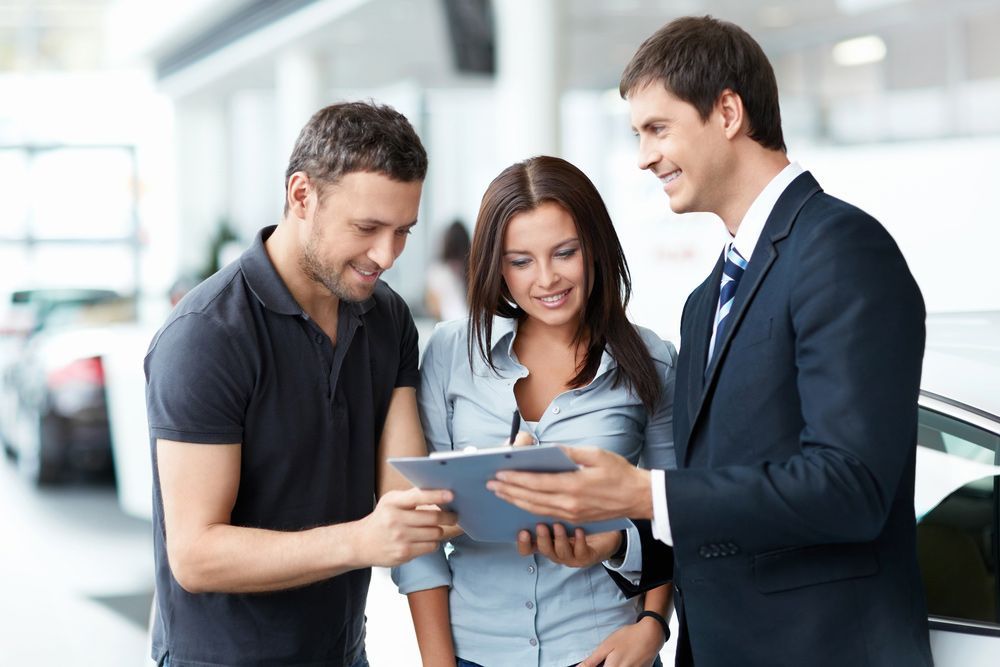 A Man and A Woman Are Looking at A Tablet in A Car Showroom — Start Learning Automotive in Brisbane, QLD