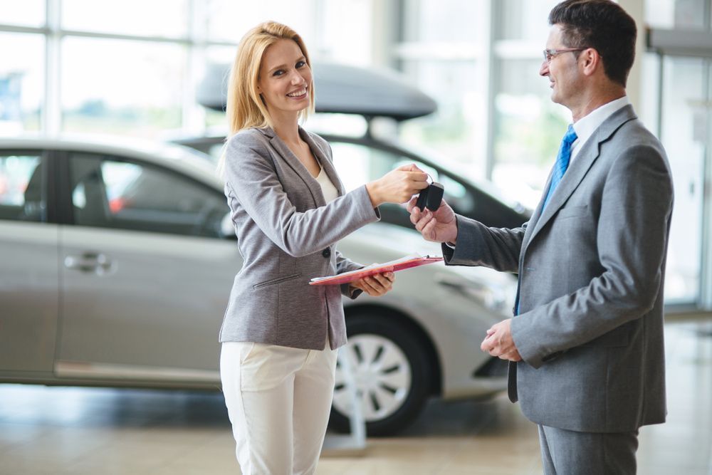 A Woman Is Giving a Man a Car Key in A Car Showroom — Start Learning Automotive in Melbourne, VIC