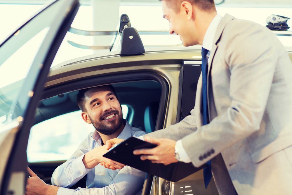 A Man Is Shaking Hands with A Car Salesman While Sitting in A Car — Start Learning Automotive in Sydney, NSW