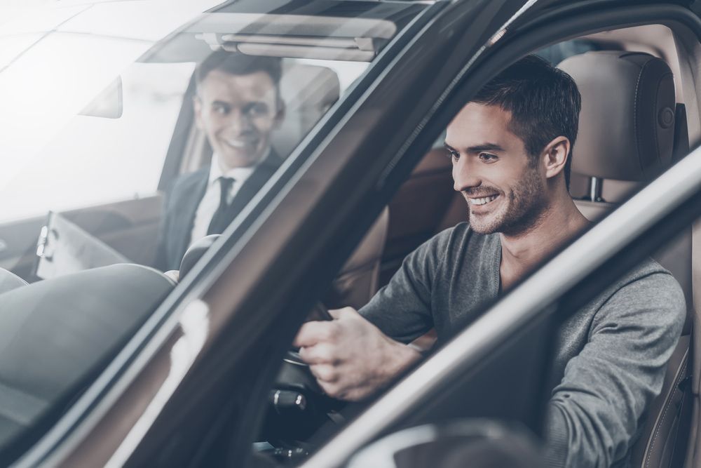 A Man Is Sitting in A Car Talking to A Car Salesman — Start Learning Automotive in Brisbane, QLD
