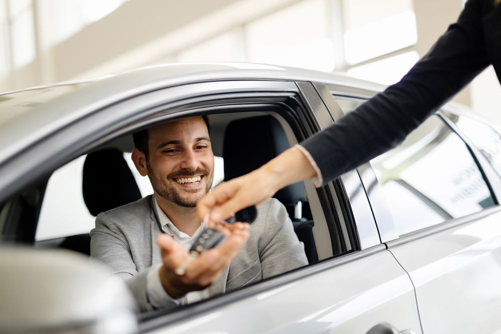 A Man Is Sitting in A Car While a Woman Gives Him a Car Key — Start Learning Automotive in Brisbane City, QLD