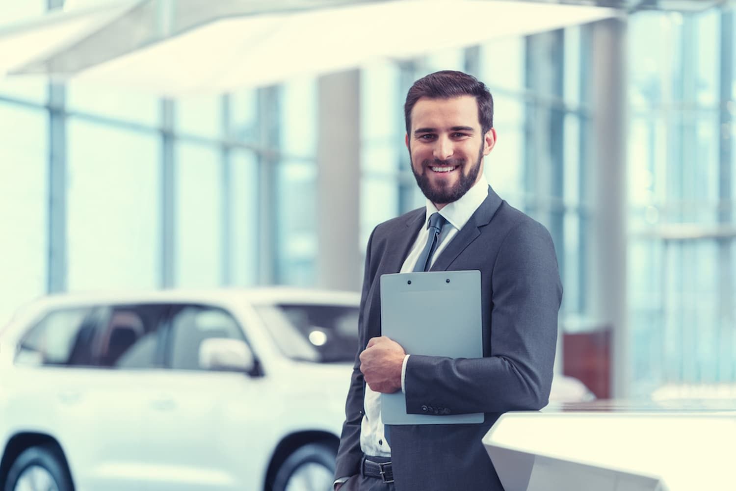 A Man in A Suit and Tie Is Holding a Clipboard in Front of A Car — Start Learning Automotive in Gold Coast, QLD