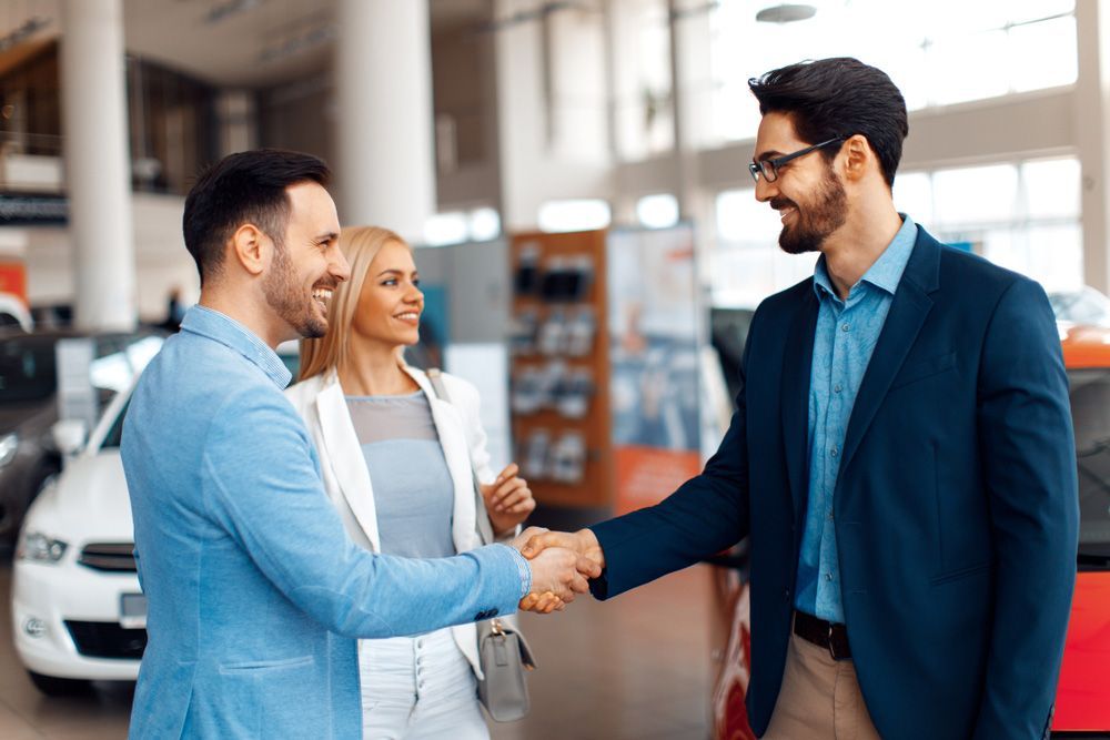 A Man and A Woman Are Shaking Hands in A Car Showroom — Start Learning Automotive in Sunshine Coast, QLD