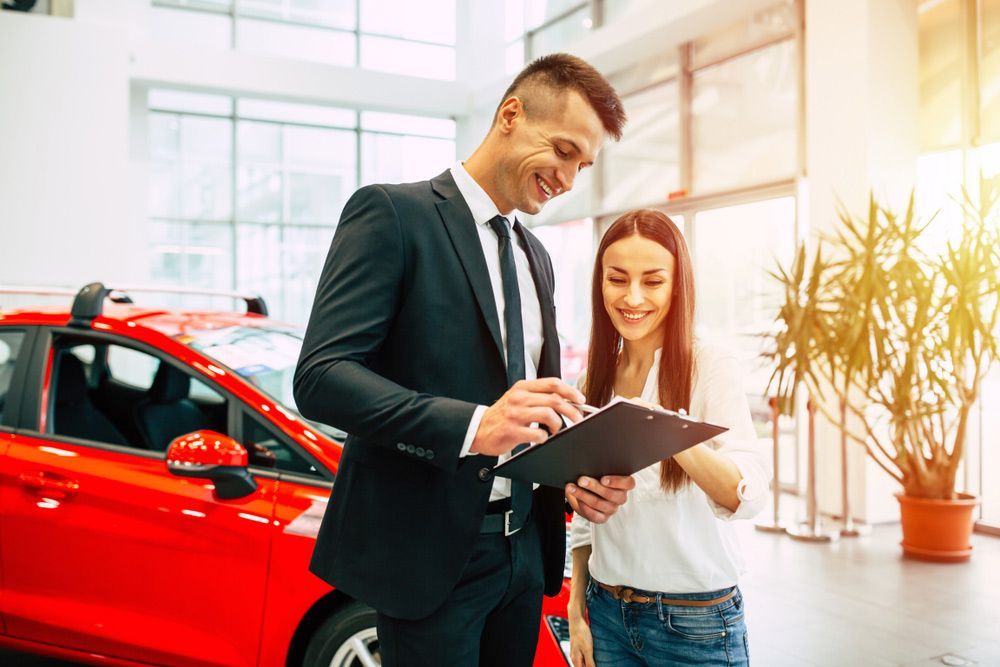 A Man and A Woman Are Looking at A Clipboard in A Car Showroom — Start Learning Automotive in Brisbane, QLD