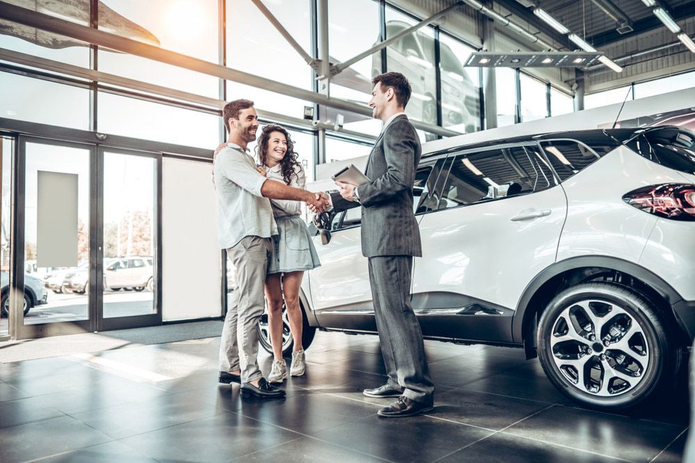 A Man Is Shaking Hands with A Woman in A Car Showroom — Start Learning Automotive in Brisbane, QLD