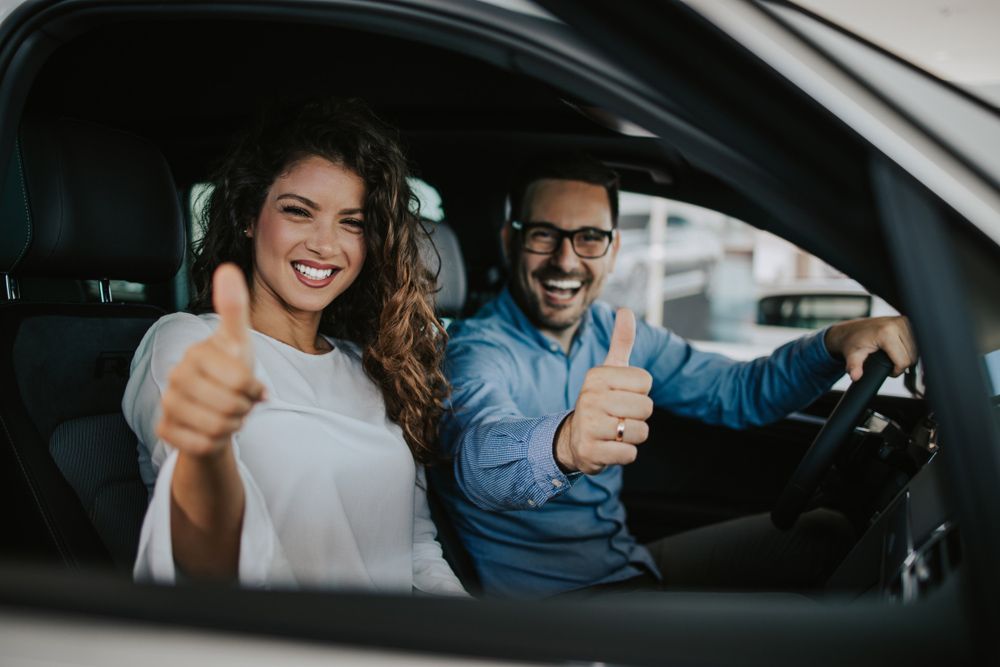 A Man and A Woman Are Giving a Thumbs up In a Car — Start Learning Automotive in Brisbane City, QLD
