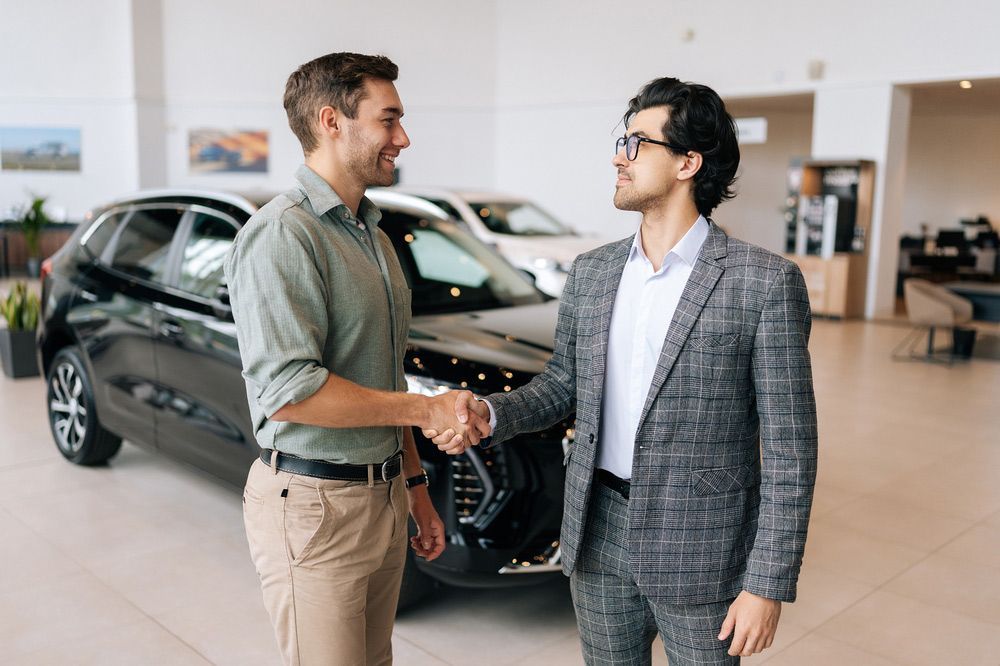 Two Men Are Shaking Hands in Front of A Car in A Showroom — Start Learning Automotive in Melbourne, VIC