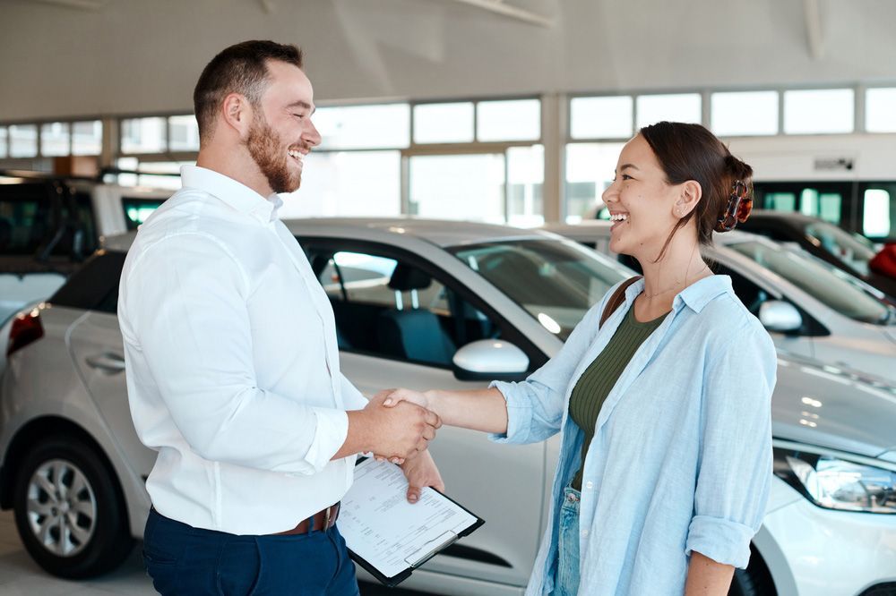 A Man and A Woman Are Shaking Hands in A Car Showroom — Start Learning Automotive in Brisbane City, QLD