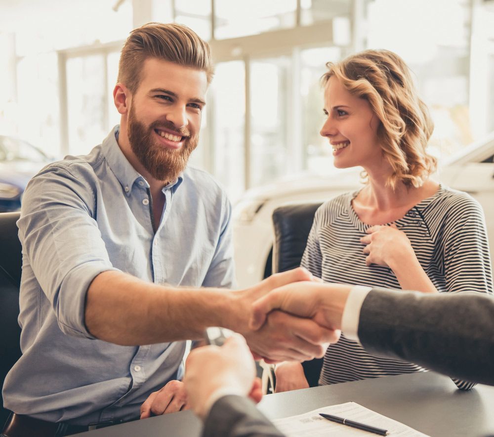 A Man and A Woman Are Shaking Hands at A Table in A Car Dealership — Start Learning Automotive in Brisbane City, QLD