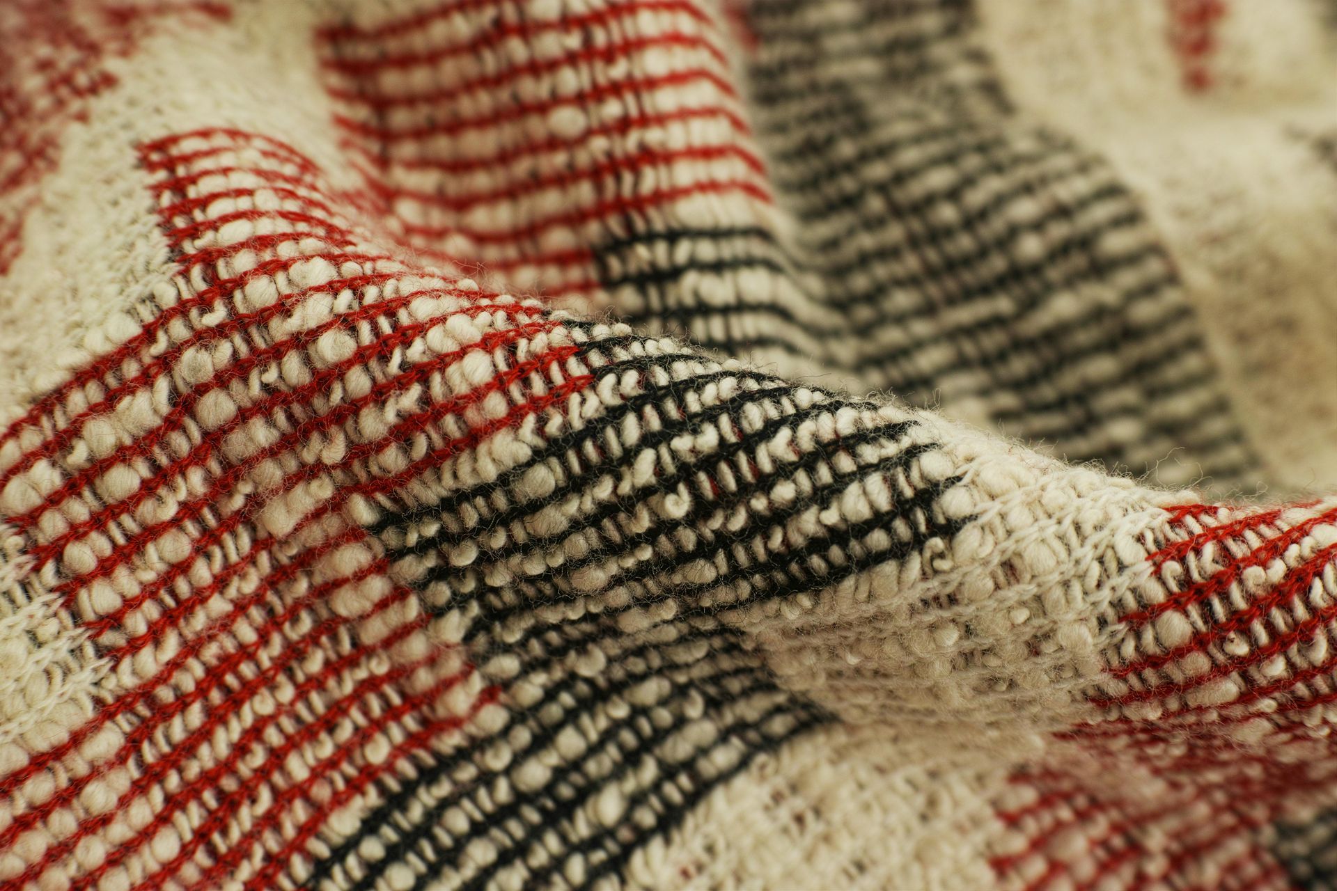 Close-up of woven fabric with red, black, and white striped pattern.