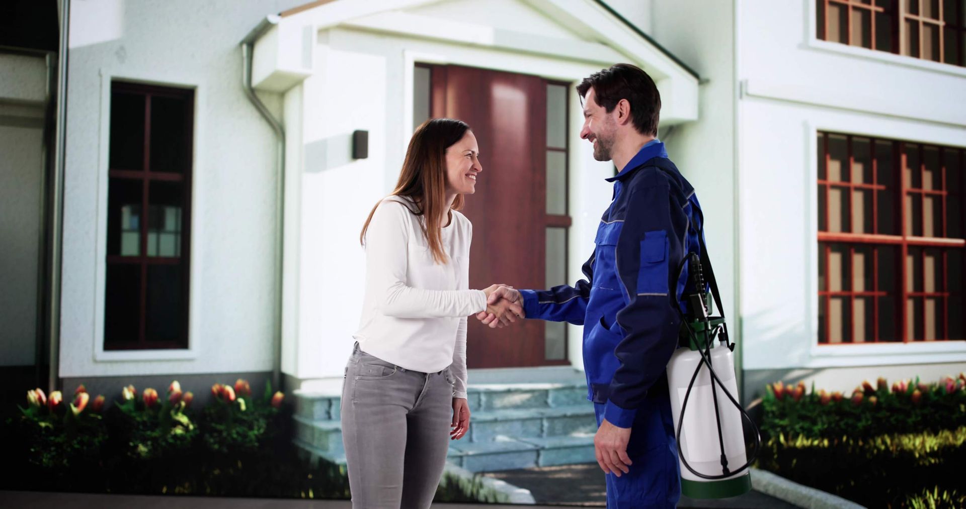 Woman shakes hands with a repairman in front of a house; both smile.