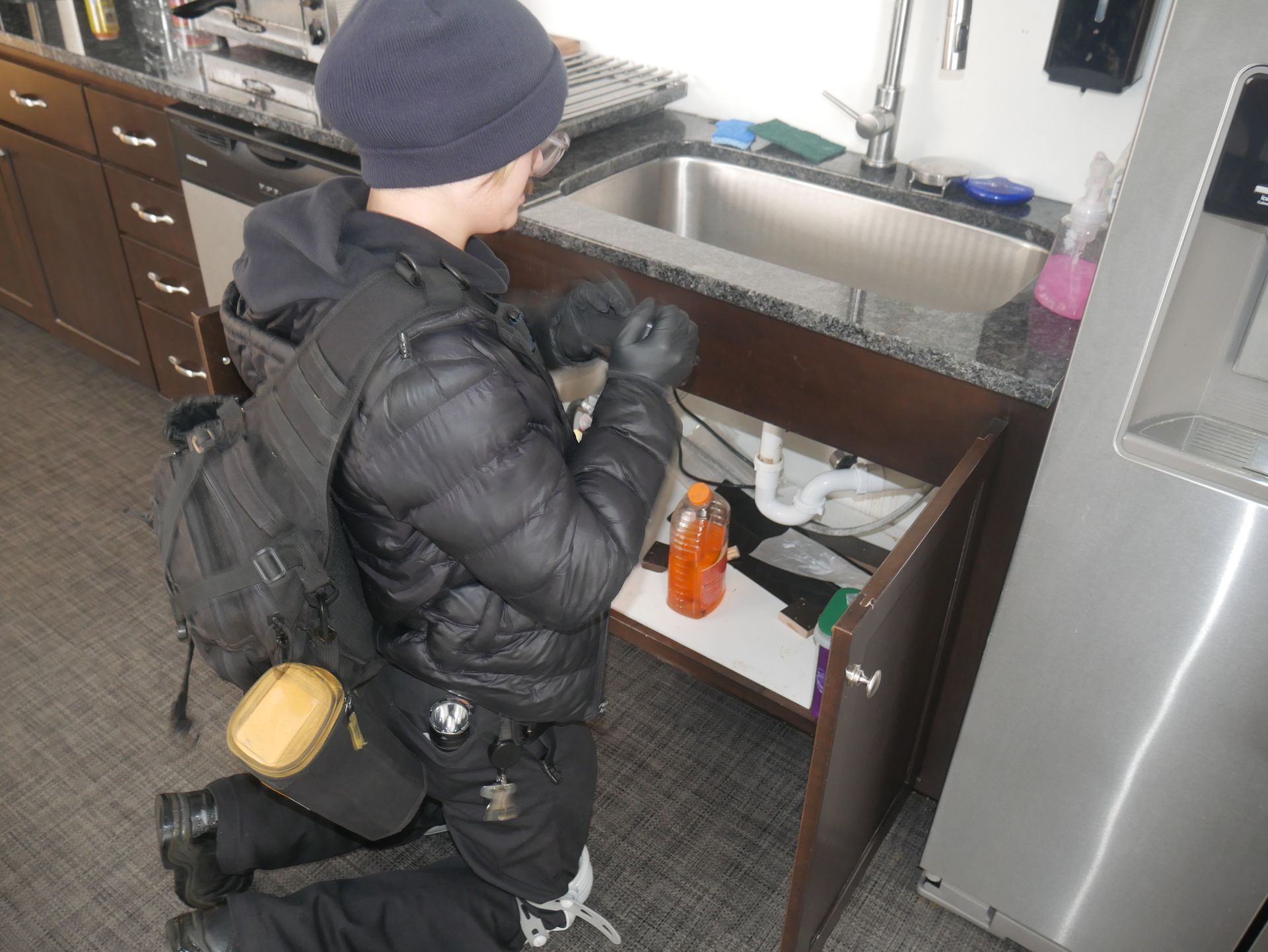 Technician checking a bait station under a kitchen sink