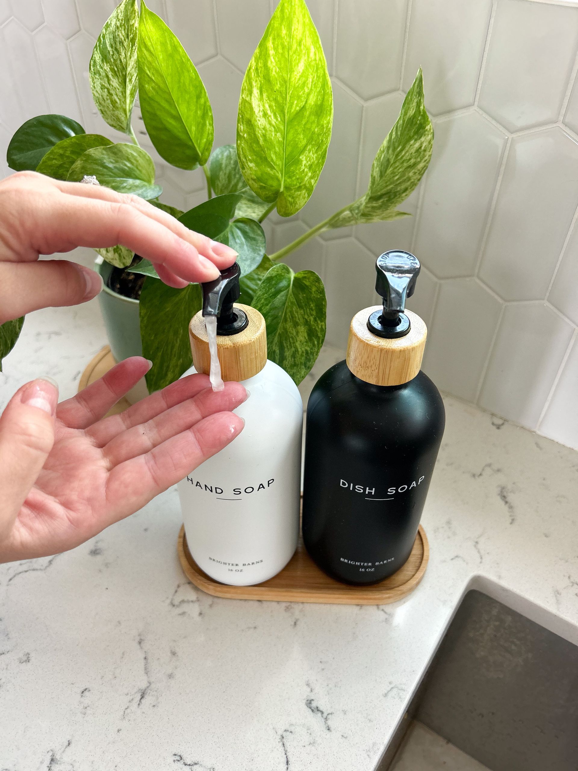 A person is applying soap to their hand in front of a sink.
