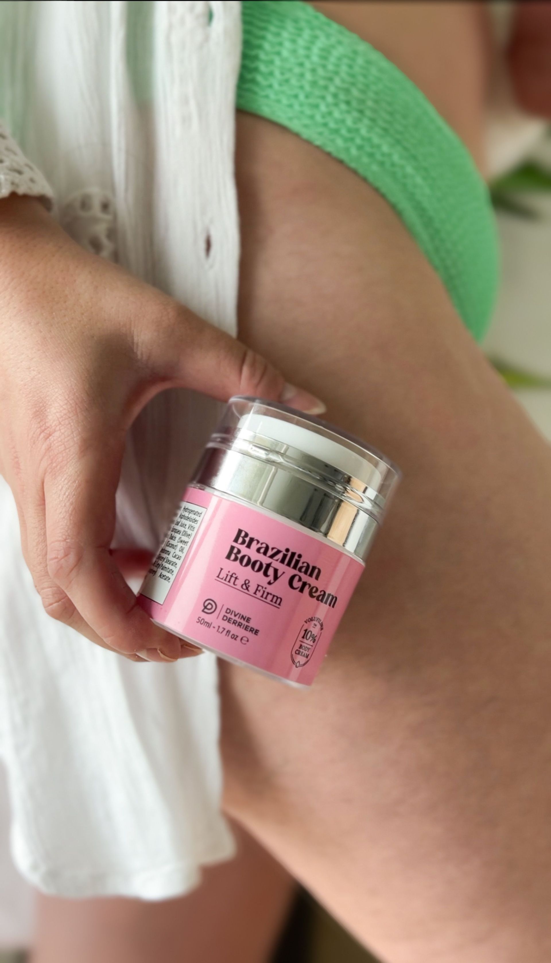 A woman in a green bikini is holding a pink jar of cream.