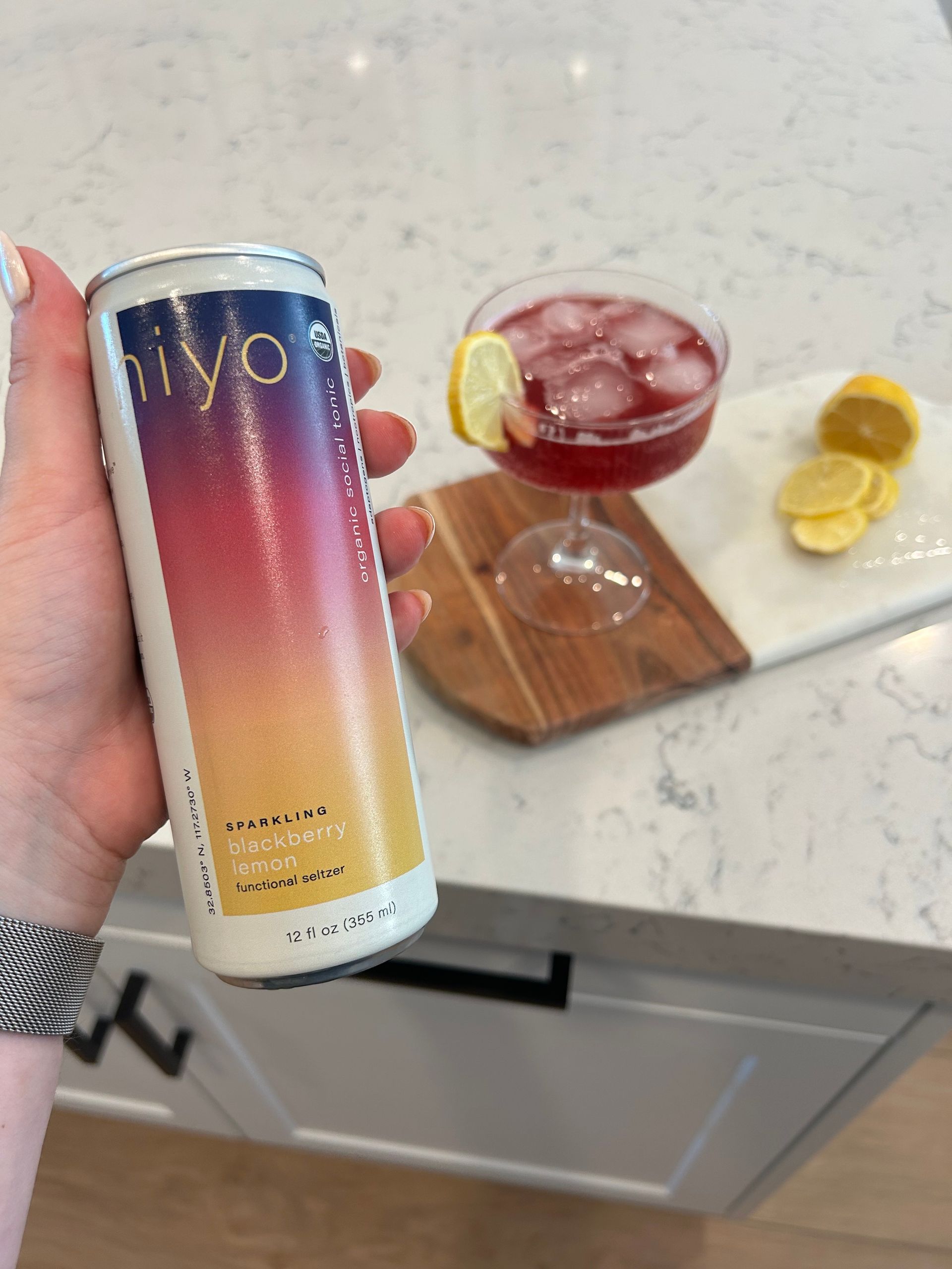 A person is holding a can of vivo next to a glass of wine.