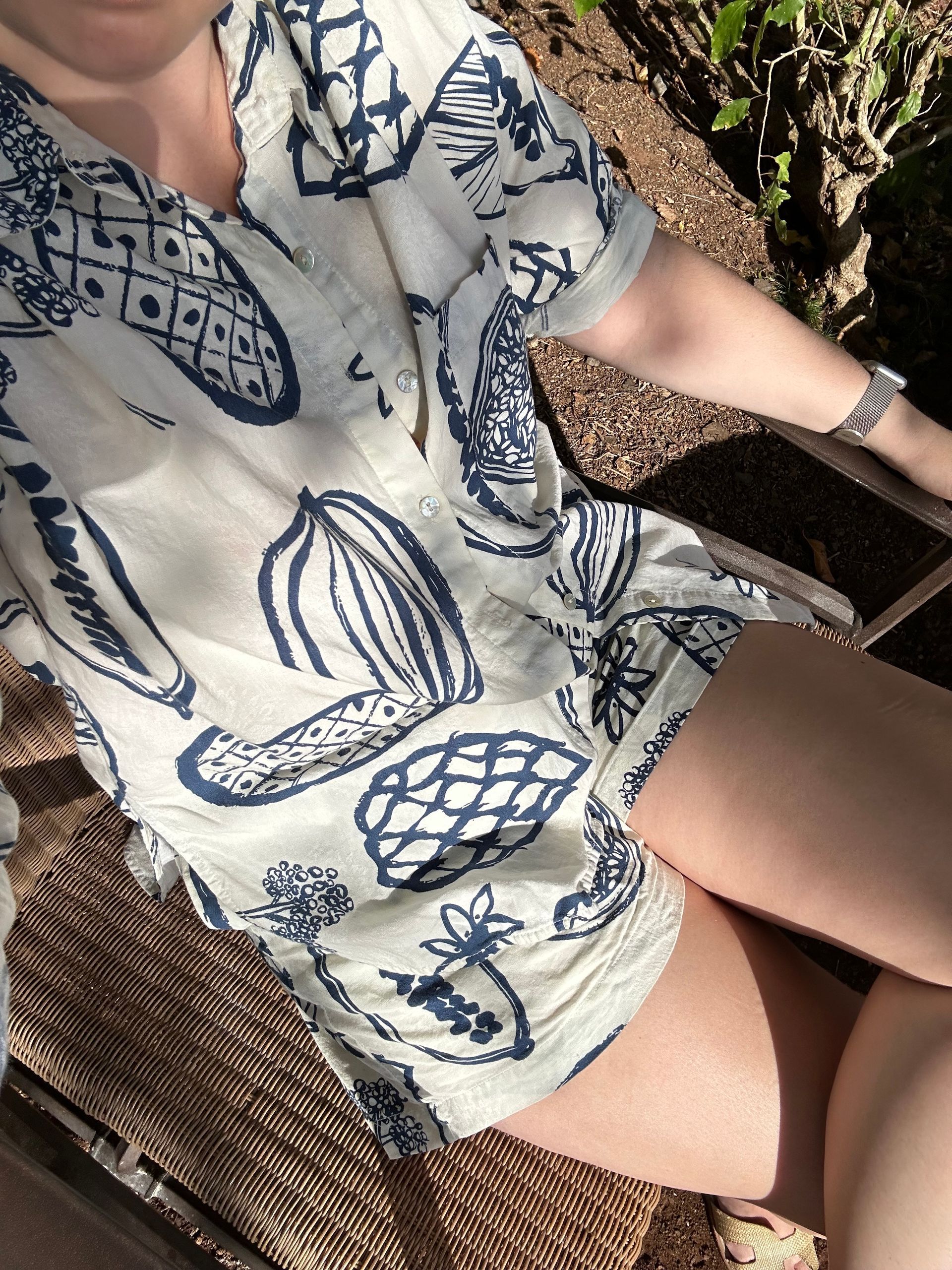A woman in a blue and white shirt is sitting on a chair.