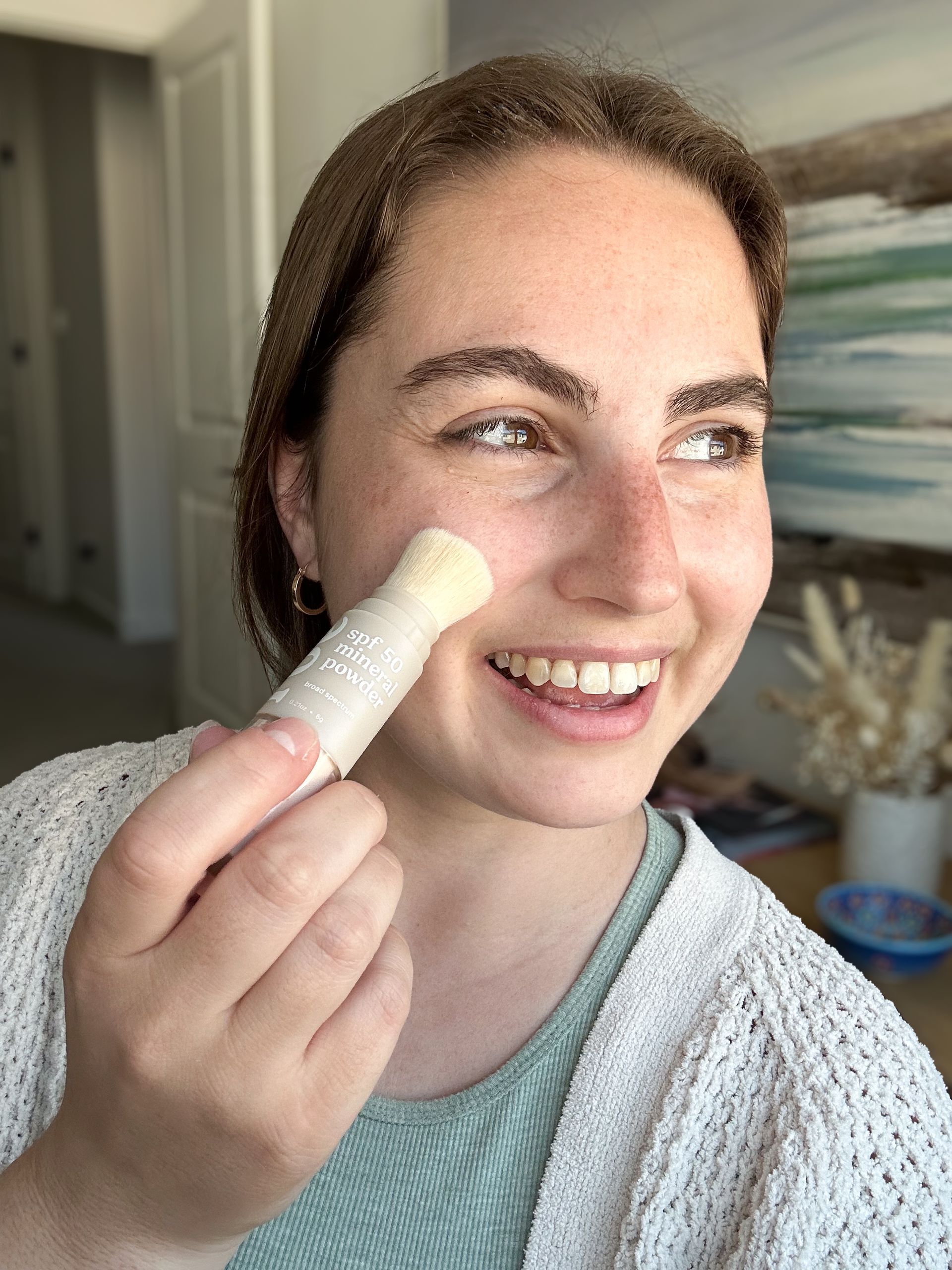 A woman is holding a stick of lip balm in front of her face.