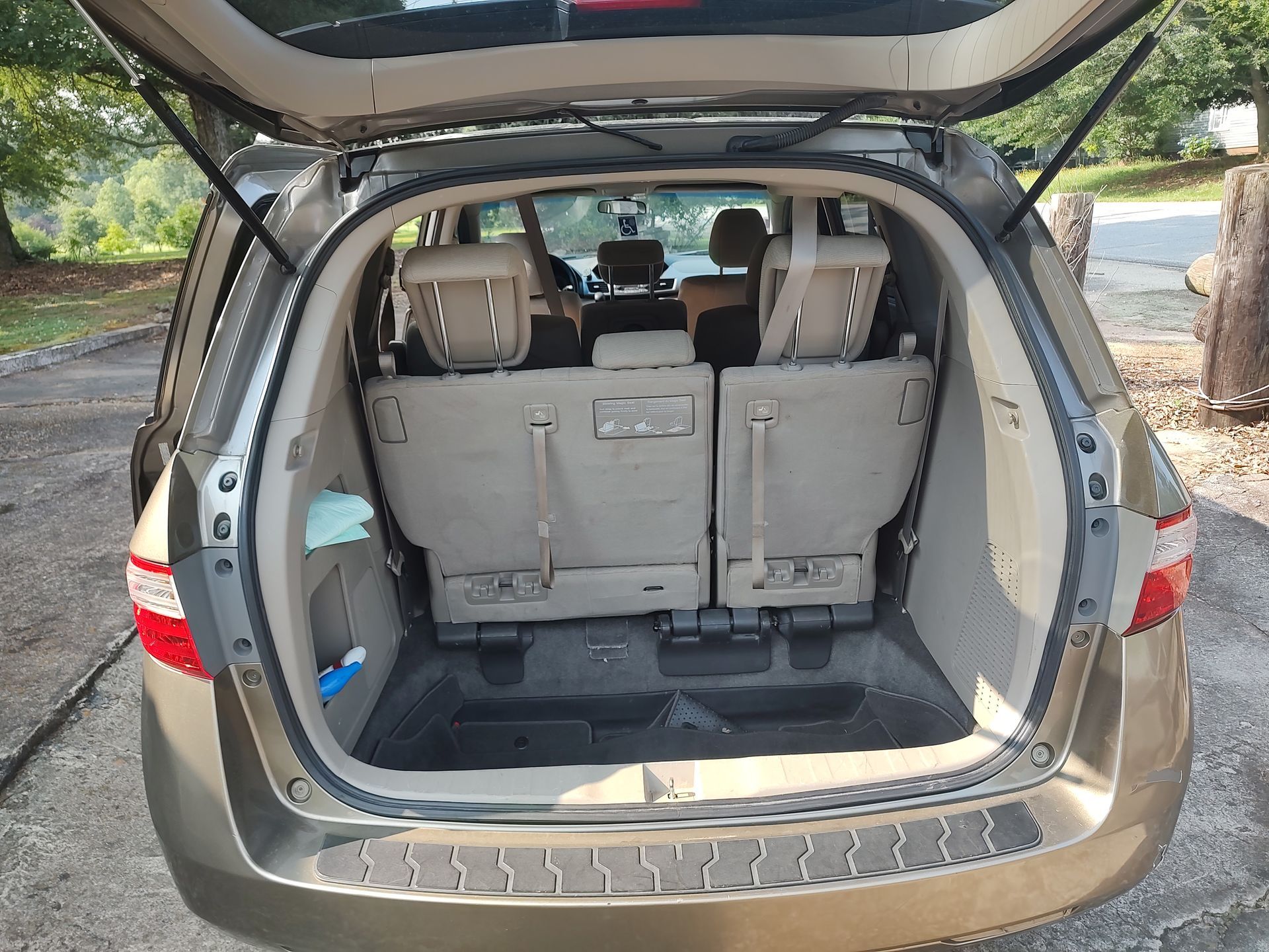 The trunk of a minivan is open and empty.