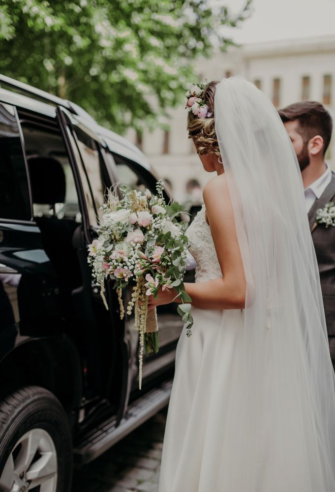 A bride and groom are getting out of a car.