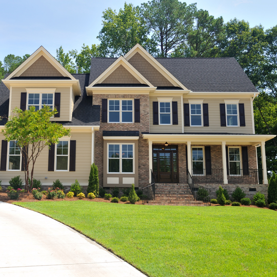Two-story house with beige siding, brick facade, black shutters, green lawn, and a driveway.